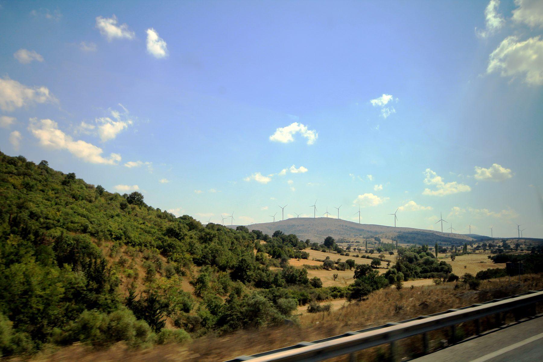 Wind turbines extending across a rural ridge in Türkiye
